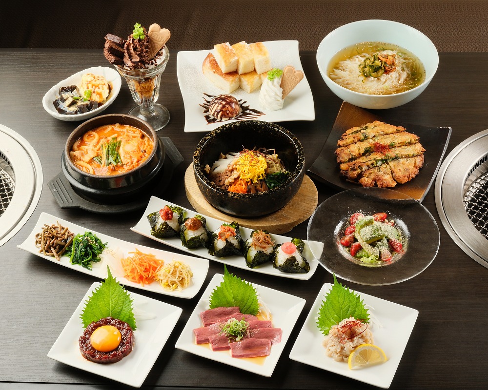 テーブルにユッケ、おにぎり、サラダ、冷麺、デザートなどの写真