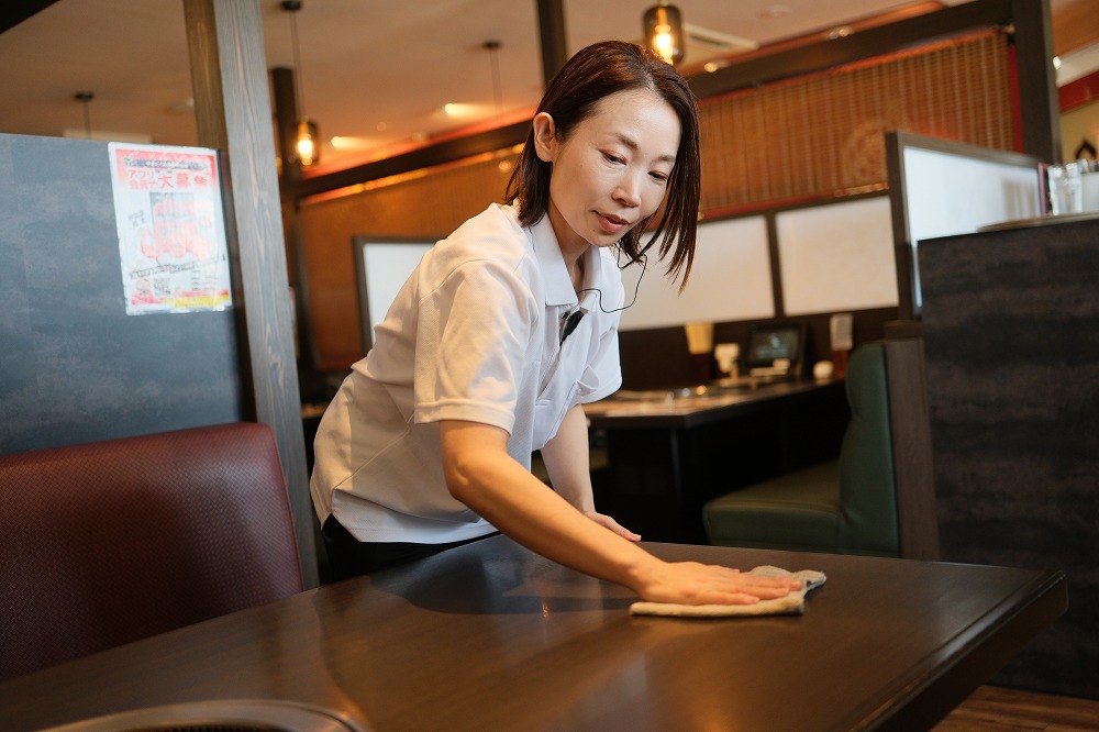 テーブルを拭いている女性スタッフ