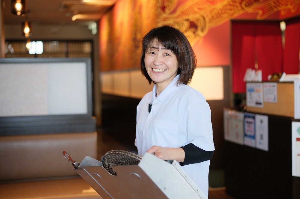 焼肉網を持った女性スタッフ