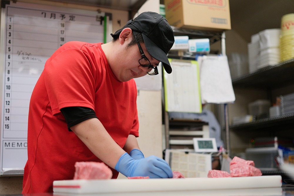 厨房でお肉を切っている男性スタッフ