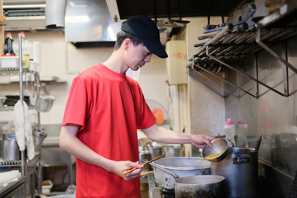 厨房で料理を仕上げる男性スタッフ