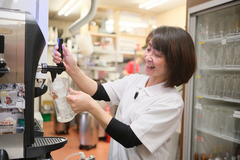 ビールサーバーでドリンクを注ぐ女性スタッフ